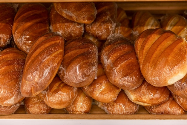 Traditional white bread in plastic packages on a wooden shelf in a store Closeup