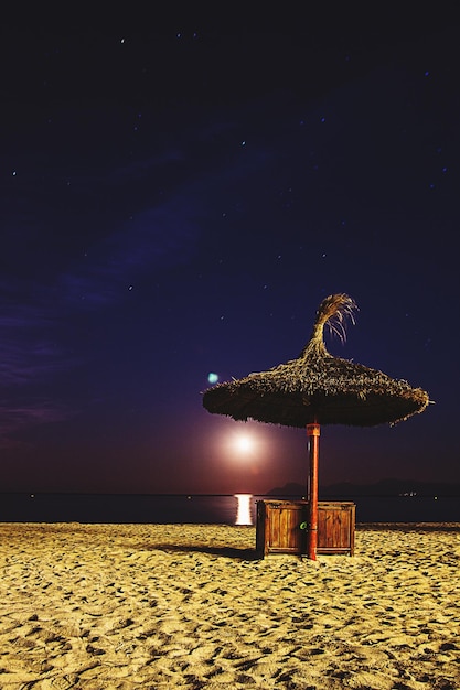 Foto tradizionale mulino a vento sulla spiaggia contro il cielo notturno