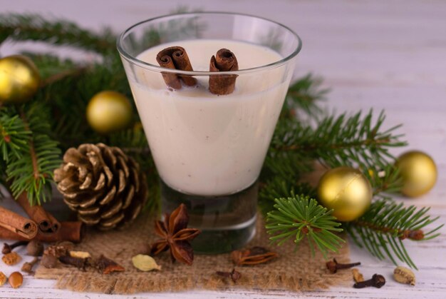 Traditional winter eggnog in glass mug with milk rum and cinnamon