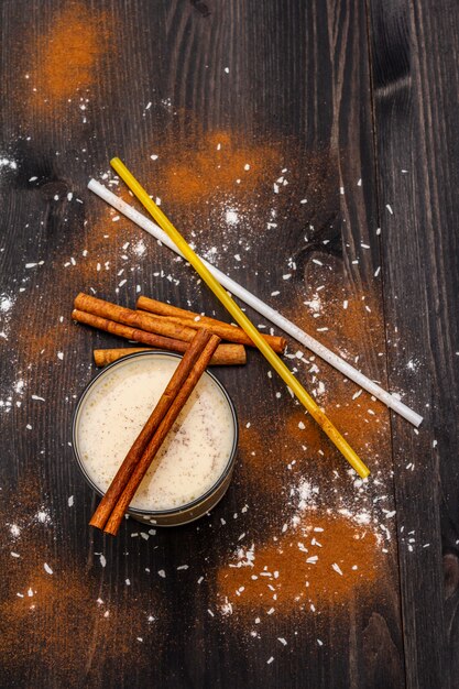 Traditional winter eggnog with milk, rum and cinnamon, sprinkle with grated nutmeg. Cocktail straws