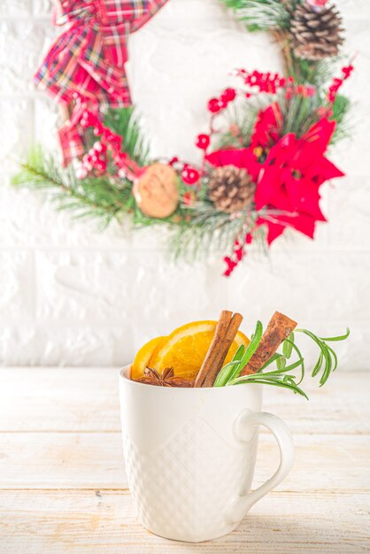 Traditional Winter Hot Alcohol Drink. Mulled Wine in a white Cup on the background of the kitchen table with Christmas decorations.