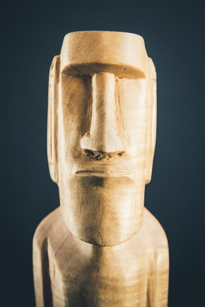 Traditional wooden statue of a moai from Easter Island. Dark background