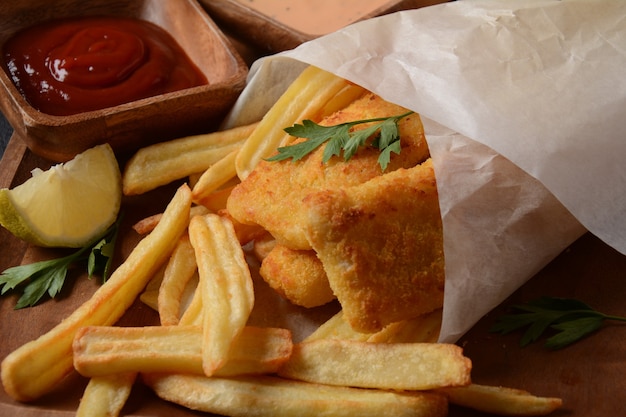 Traditioneel Engels eten - Fish and Chips. Gebakken visfilets en krokante frietjes geserveerd met ketchup en huisgemaakte tartaarsaus.