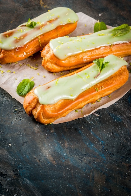 Traditioneel Frans dessert. Mojito Eclairs met limoenschil en muntblaadjes, op donkerblauw, copyspace