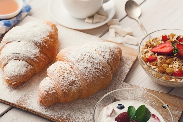 Traditioneel Frans ontbijtmenu. Yoghurt met verse bessen, glas sinaasappelsap, muesli en croissants op houten tafel, kopieer ruimte