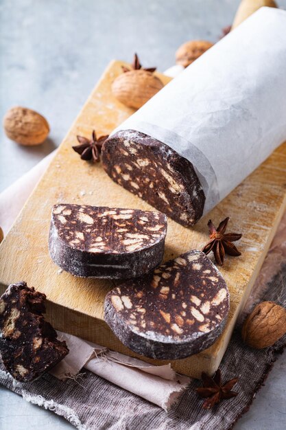 Foto traditioneel italiaans dessert - kerstchokoladesalami met gebroken koekjes en walnoten op tafel