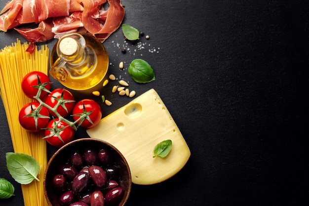 Traditioneel Italiaans eten met de kaasolijven van spaghettitomaten en olie op donker