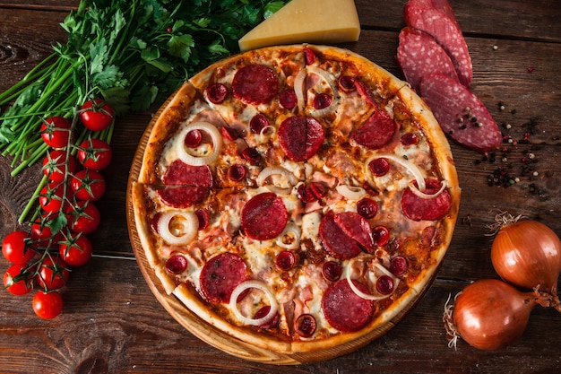 Traditioneel Italiaans eten. Verse pizza op rustieke houten tafel met ingrediënten bovenaanzicht. Menufoto.