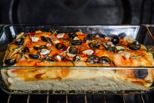 Traditioneel Italiaans vegetarisch focacciabrood met olijven, rozemarijn en knoflook