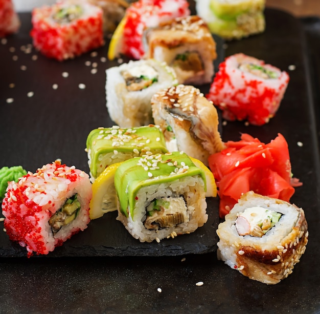 Foto traditioneel japans eten - sushi, broodjes en saus op een zwarte achtergrond.