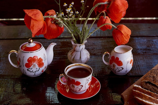 Traditioneel maanzaadbroodje met kopje thee en melk in de buurt van papaversbloemen en gerechten met papaversornamenten Heerlijk ontbijt in de zomer Lifestylefotografie