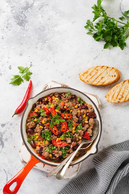 Traditioneel Mexicaans eten - Chili con carne met gehakt en groentenstoofpot in tomatensaus in een gietijzeren pan