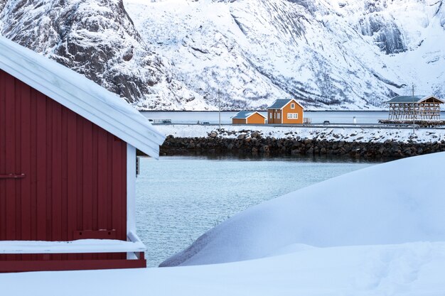 Traditioneel noors houten huis rorbu om aan de oever van de fjord en de bergen in de verte te staan. Lofoten eilanden. Noorwegen.
