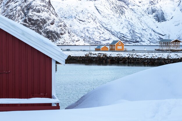 Traditioneel noors houten huis rorbu om aan de oever van de fjord en de bergen in de verte te staan. lofoten eilanden. noorwegen.