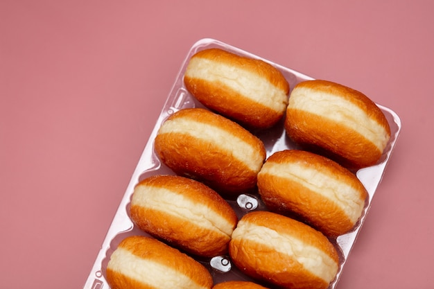 Traditioneel poetsmiddel donuts in een doos op roze achtergrond