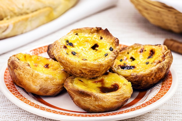 Traditioneel Portugees dessert van pastel de nata en bree de lis en brood op de achtergrond geserveerd met koffie typische Lissabonse snoepjes