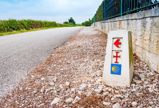 Traditioneel schelpteken en pijl onderweg geschilderd. Richtingsteken voor pelgrims op de Saint James-manier, Camino de Santiago de Compostela, Spanje