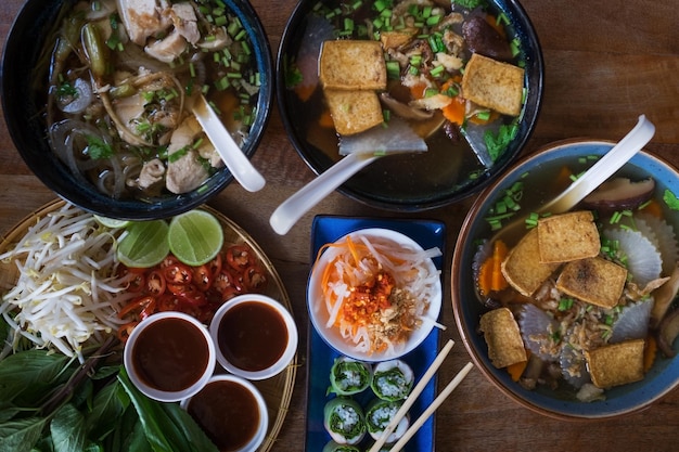 Traditioneel Vietnamees eten Soepenbroodjes en verse kruiden Platen op een houten ondergrond