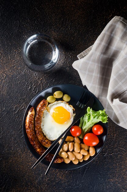 Traditioneel volledig Engels ontbijt met gebakken eieren, worstjes, bonen, tomaten, croissant en koffie