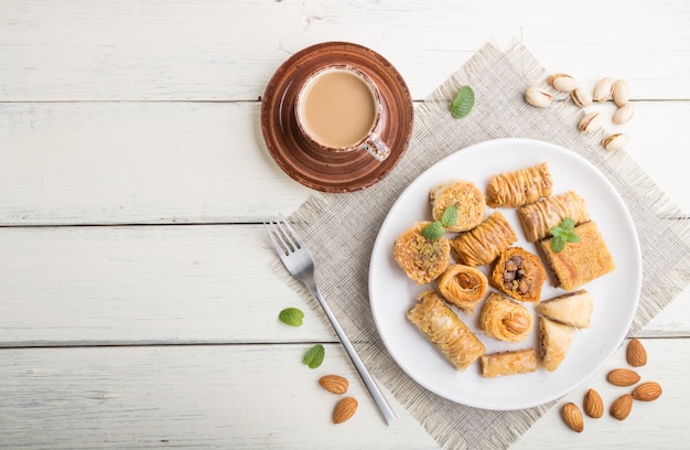 Traditionele Arabische snoepjes (kunafa, baklava) en een kopje koffie op een witte houten achtergrond. bovenaanzicht, kopie ruimte.