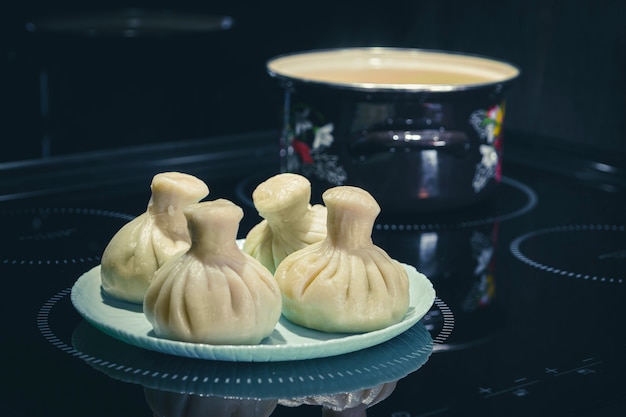 Foto traditionele aziatische dumplings en pot op zwarte achtergrond. eigengemaakt.