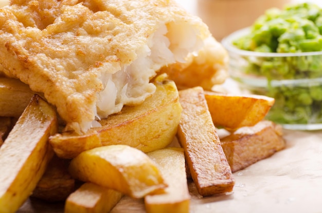 Traditionele Britse streetfood fish and chips met papperige erwten op perkamentpapier