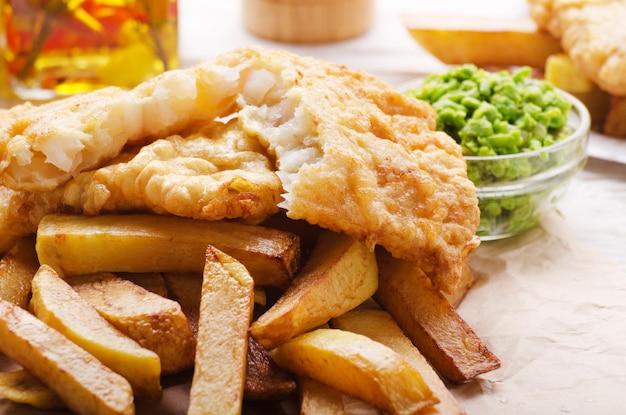 Traditionele Britse streetfood fish and chips met papperige erwten op perkamentpapier