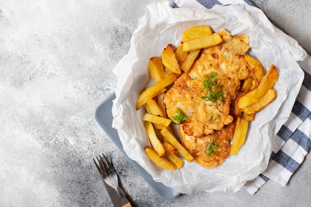 Traditionele Britse vis met chips. Op een grijze plaat en grijze betonnen achtergrond. Ruimte voor tekst. Bovenaanzicht, plat lag