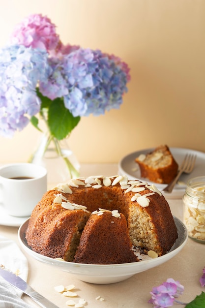 Traditionele bundt cake, zelfgemaakte gebak gebakken ronde cake met koffiekopje en bloemen op achtergrond