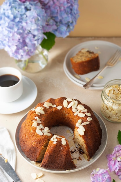 Traditionele bundt cake, zelfgemaakte gebak gebakken ronde cake met koffiekopje en bloemen op achtergrond