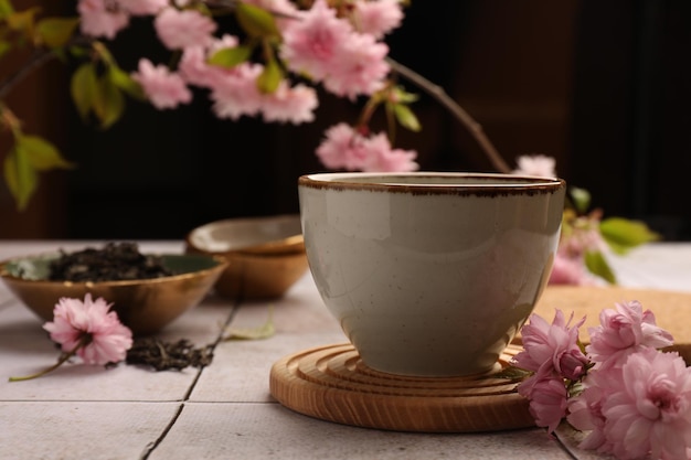 Foto traditionele ceremonie beker gebrouwen thee en sakura bloemen op een tegeltafel close-up