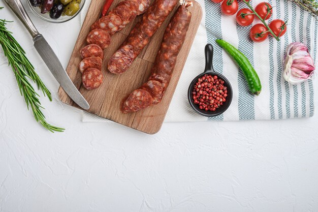 Traditionele chorizo snijdt met kruiden en ingrediënten op een witte ondergrond, bovenaanzicht met kopie ruimte.