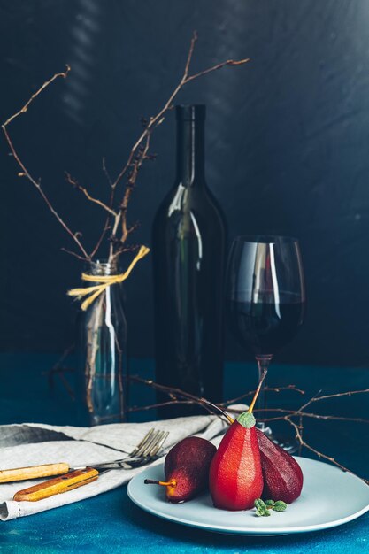 Traditionele dessertperen gestoofd in rode wijn met chocoladesaus op plaat op blauw betonnen oppervlak Concept voor romantisch dinerdessert Eenvoudige dessertpeer in Paleo-stijl gepocheerd in granaatappelsap