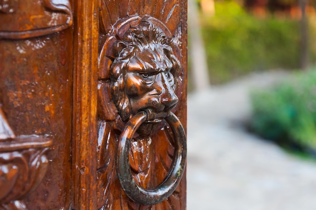 Traditionele deurklopper op een gesneden houten deurijzer gemaakt met het gezicht van een leeuw