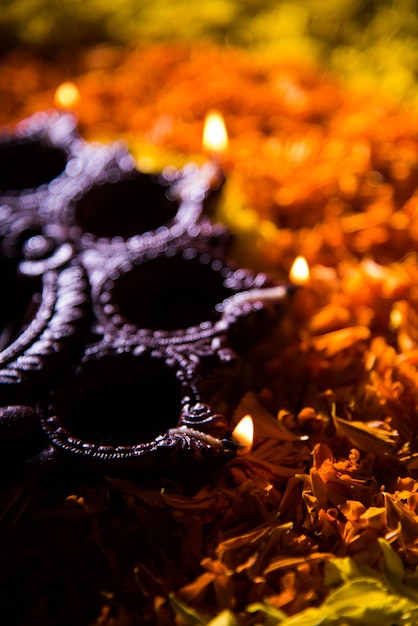 Traditionele diya of olielamp verlicht op kleurrijke rangoli bestaande uit bloemblad, op het festival van lichten genaamd diwali of deepawali, selectieve focus