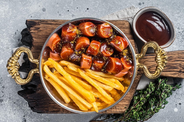 Traditionele Duitse curryworstworst geserveerd met frites of frietjes in een pan Grijze achtergrond Bovenaanzicht