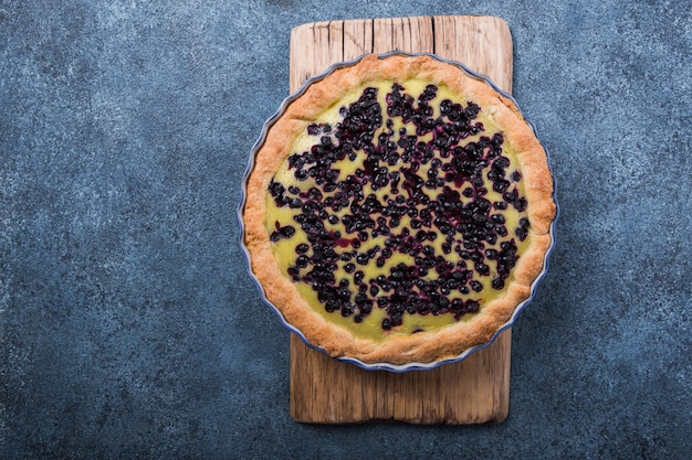 Traditionele franse clafoutis van het zoete fruitdessert met bosbessen op blauwe concrete oppervlakte. gezond glutenvrij voedselconcept met exemplaarruimte.