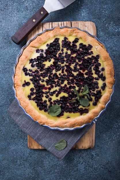 Traditionele franse clafoutis van het zoete fruitdessert met bosbessen op blauwe concrete oppervlakte. gezond glutenvrij voedselconcept met exemplaarruimte.