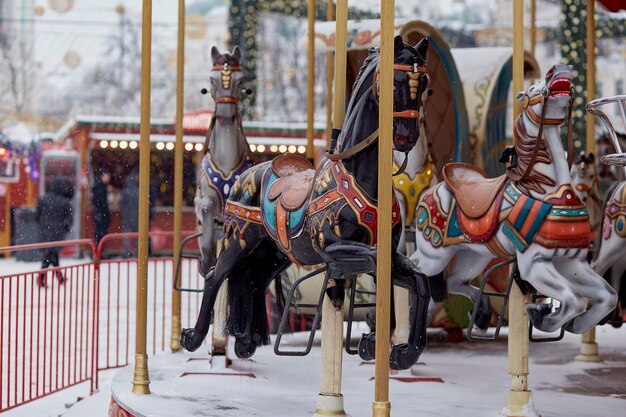 Traditionele Franse kerstcarrousel op het feestelijke plein met versieringen op een besneeuwde dag Merry Christmas