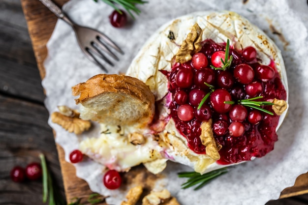 Traditionele Franse zelfgemaakte gebakken Camembert-kaas met veenbessen en noten. rozemarijn en stokbrood.