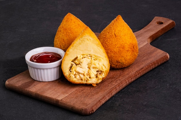 Traditionele gebakken coxinha op een houten bord over leisteen.