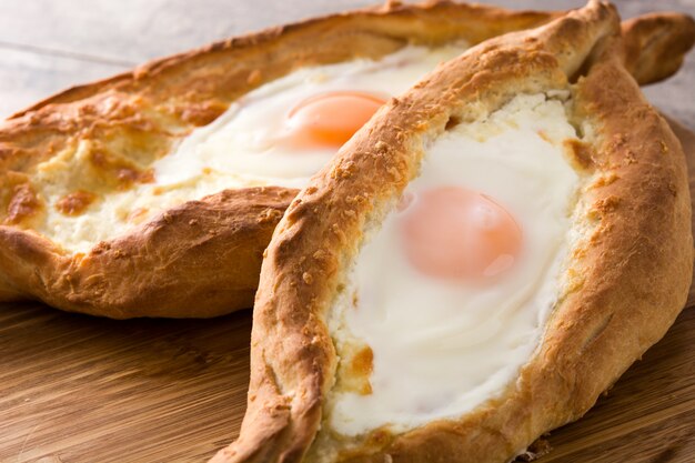 Traditionele Georgische khachapuri van Adjarian met kaas en ei op houten lijst dichte omhooggaand