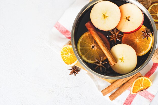 Traditionele glühwein in pot met kruiden op wit