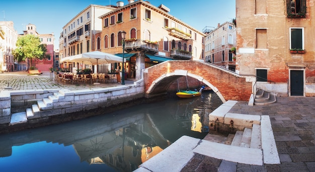 Traditionele gondels op smal kanaal tussen kleurrijke historische huizen in Venetië, Italië