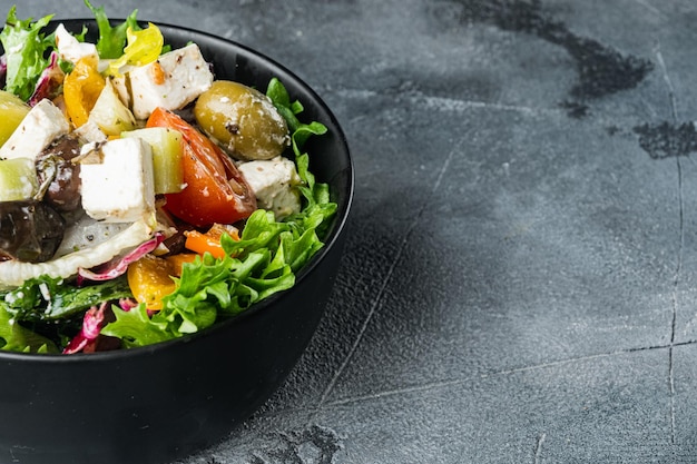 Traditionele Griekse salade met verse groenten, feta en olijven, op grijze achtergrond met kopieerruimte voor tekst