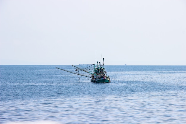 Traditionele groene Thaise vissersboot die in de baai van Thailand dichtbij koh chang drijven op dag de heldere hemel.