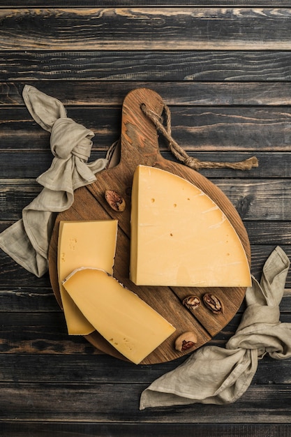 Foto traditionele harde parmezaanse kaas wordt in stukjes gesneden op een donkere houten plank. een uitstekend product voor het bereiden van gevogeltegerechten, soepen, pasta. donkere houten achtergrond. bovenaanzicht