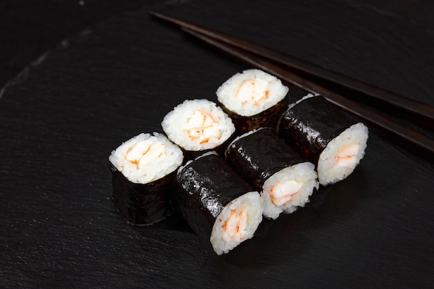 Traditionele heerlijke verse sushi rolletjes met garnalen op een zwarte achtergrond Sushi roll met rijst roomkaas avocado zalm sesam Sushi menu Japanse keuken restaurant