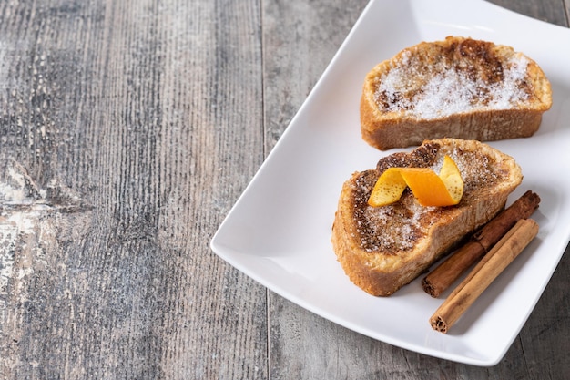 Traditionele huisgemaakte Spaanse torrijas versierd met kaneel en sinaasappelschil op houten tafel