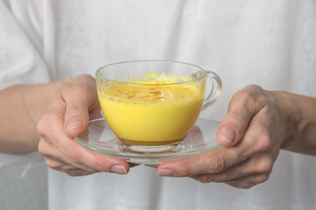 Traditionele Indiër drinkt kurkuma gouden melk in een hand. Een remedie tegen virussen en vele ziekten.